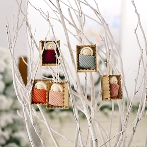 Christmas wooden doll ornaments set in knit hats hanging on white branches for holiday decor