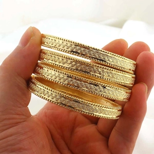Dettaglio macro di bracciali a spirale placcati oro 24k con trame incise a rilievo