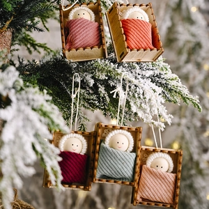 Handmade wooden doll ornaments set hanging on snowy pine branches with festive bokeh