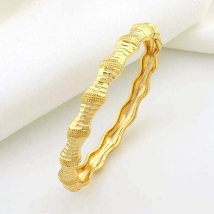 Detailopname van de golvende gouden armband met een gelaagd bamboe-stijl getextureerd design