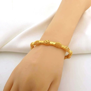 Dettaglio di un bracciale dorato con perle opache e motivi geometrici sferici traforati