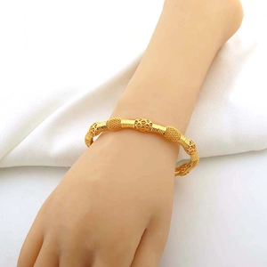 Dettaglio del bracciale dorato con motivi a rombi traforati e perle satinate su seta
