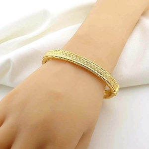 Bracciale rigido intrecciato placcato oro 24k con bordi a perline su sfondo bianco