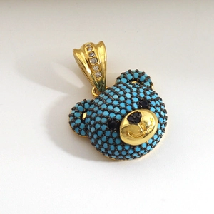 Macro shot of bear pendant with blue stones and zircon-encrusted gold-plated hook