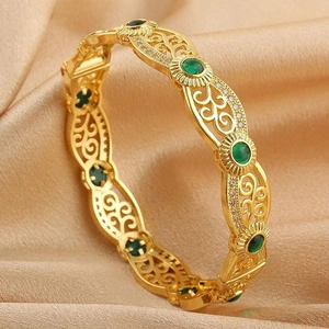 Detail showing vintage 18K gold plated hollow bracelet with green gems and zircons