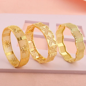 Detail van 18k vergulde armbanden met opengewerkt bloemmotief en geometrische ontwerpen