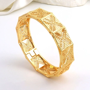 Dettaglio di un bracciale placcato oro 24K con motivi geometrici cavi e chiusura a cerniera