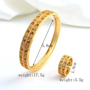 Macro detail of gold plated jewelry set with hollow patterns and red crystal accents
