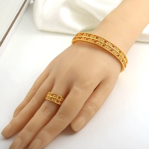 Detail of gold hollow-out bangle and ring set featuring red and white zircon inlays