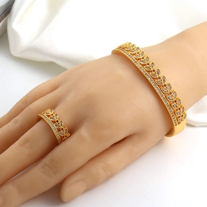 Detail of luxury gold jewelry set featuring double-row zircon ring and matching bangle