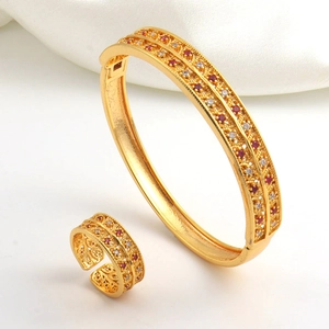 Close-up of gold-plated hollow jewelry set with red and white zircon stones on silk