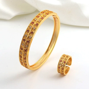 Detail of luxury gold-plated bangle and ring set with double-row red and white stones