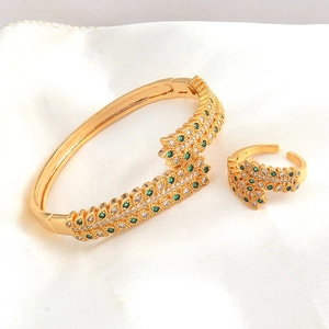 Macro shot of gold-plated leaf jewelry set featuring green crystals and white zircons