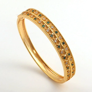 Detail of gold double-row hinged bangle featuring green and white cubic zirconia stones