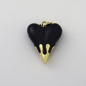 Close-up of heart-shaped pendant with black enamel top and gold dripping metal detail