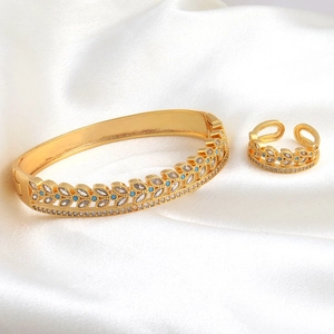Macro detail of gold wheat leaf jewelry set with zircons on white satin fabric