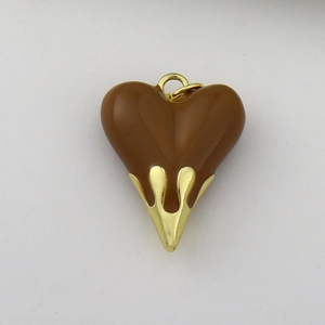 Detail of brown enamel heart pendant with fluid gold metal casing for jewelry making