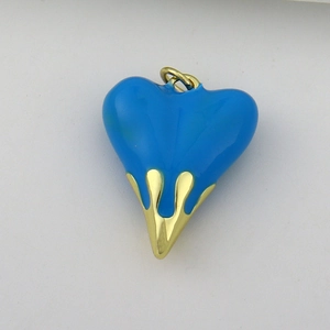 Detail of blue enamel heart pendant with golden liquid drip design and metallic loop