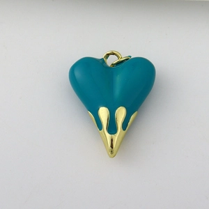 Detail of a solid heart-shaped pendant with teal enamel and gold-plated metal casing