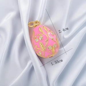 Pink enamel egg pendant with gold scrollwork and crystals, measuring 2.4cm by 1.55cm