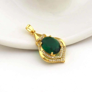 Detail view of 18k gold plated windmill pendant with oval green gemstone and white zircons