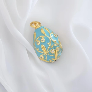 Sky blue Fabergé style egg pendant with golden floral filigree and sparkling crystals