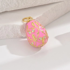 Detailed close-up of a pink Faberge-style egg pendant with gold vine relief and zircon