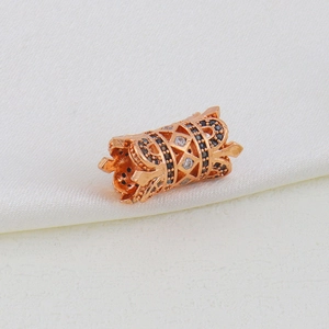 Macro shot of rose gold cylinder bead charm with black zircons and crown details
