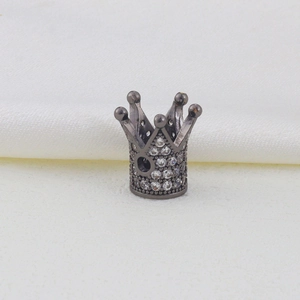Macro detail of gunmetal crown bead with pavé zircon crystals on white silk background