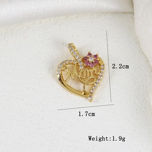 Macro view of gold Mom heart pendant with zircons and pink flower detail on white stone