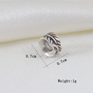 Vista macro del charm a piuma d'argento vintage da 0,7 cm con texture incise