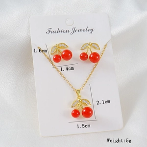 Detailed view of cherry jewelry set featuring red beads and cubic zirconia on silk