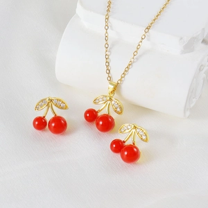 Elegant gold cherry jewelry set with red stones and zircon crystals on white silk background