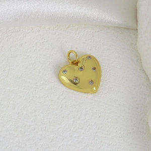 Golden heart pendant with sparkling cubic zirconia on a white silk background