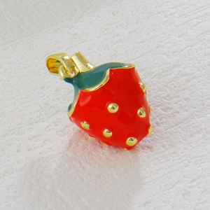 Detailed view of a gold-plated strawberry pendant with red enamel and zircon accents