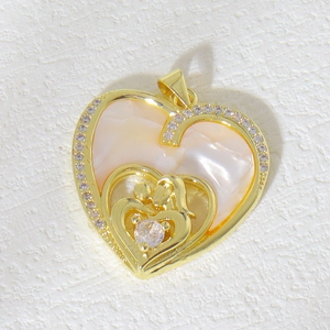 Macro shot of gold heart pendant with iridescent mother of pearl and mother-child relief
