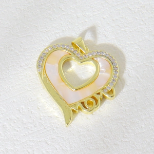 Macro view of gold heart pendant with white shell inlay, cubic zirconia and MOM text