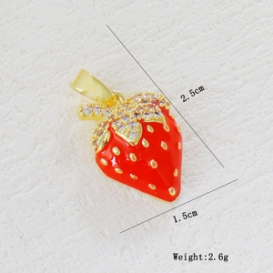 Macro detail of a 2.5x1.5cm red strawberry pendant with gold plating and zircons