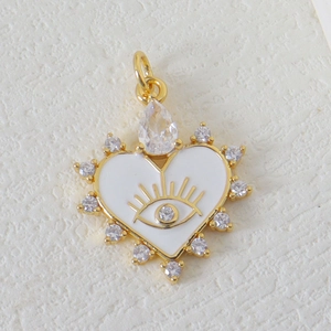 Macro shot of gold heart pendant with white enamel, evil eye motif, and zircon inlay