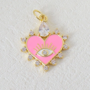 Macro detail of gold plated heart pendant with pink enamel, evil eye, and zircon accents