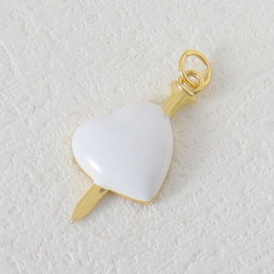 Macro detail of heart and arrow pendant with white enamel and golden metal finish
