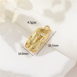 Macro detail of a 18k gold-plated twisted palm pendant with a round white zircon stone