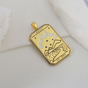 Detalle macro del colgante de carta del tarot dorado con relieve de luna y estrellas