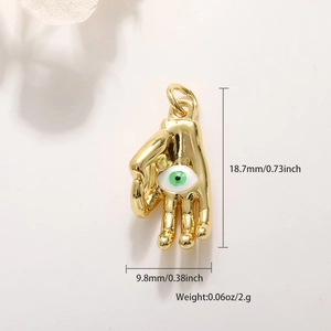 Detailed view of a gold-plated Hamsa hand charm with green eye and dimension markings