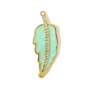 Macro view of gold plated leaf pendant with green enamel and sparkling zircon inlay