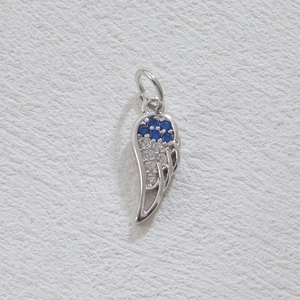 Pendentif aile en argent avec zircons bleus et blancs sur cuir beige texturé