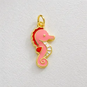 Detailed view of seahorse charm pendant with pink enamel and gold plating finish