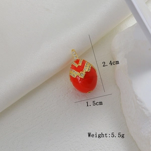 Macro view of red enamel egg pendant with gold pattern and micro zircon insets