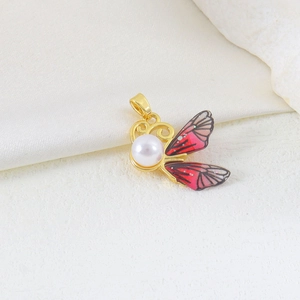 Macro shot of butterfly pendant with red gradient wings and white pearl on gold base