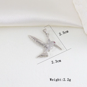 Detailed macro view of hummingbird pendant with white zircon pavé and red gemstone eye
